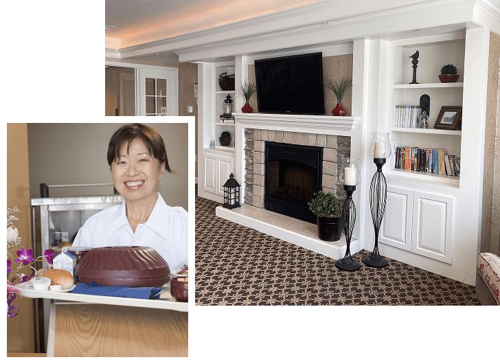 A cozy living room with a fireplace, flat-screen TV above, and built-in white shelves on either side holding books and decorative items. Inset shows a smiling woman in a white shirt standing behind a table with a cake and flowers.